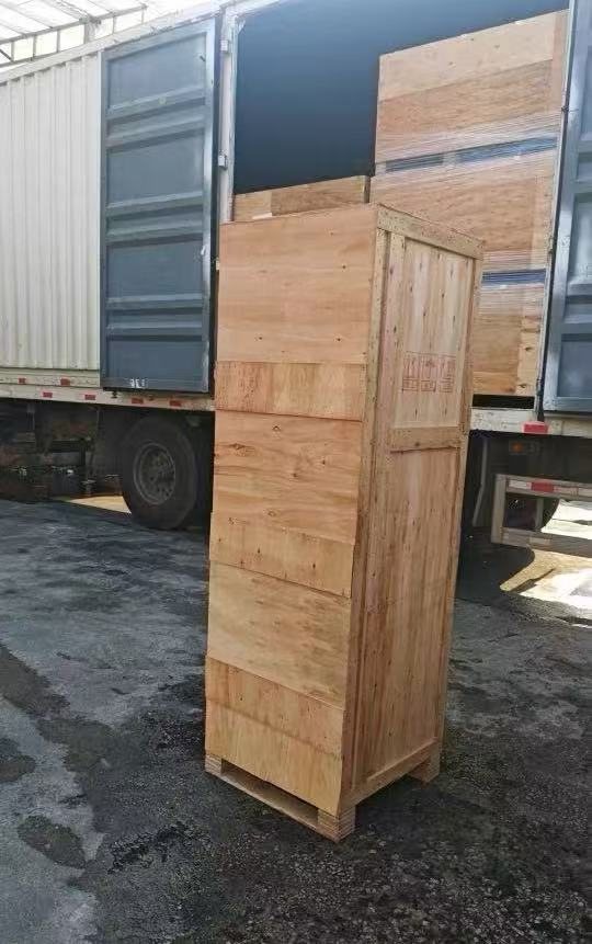 A machine packed in a wooden export crate beside a container truck