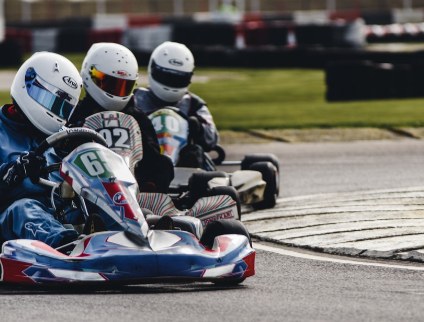 Go-kart drivers wearing helmets on a track